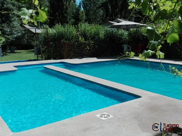Piscina azul cristalina con trampolín y sombrillas rodeada de árboles en Jardín Salto del Laja