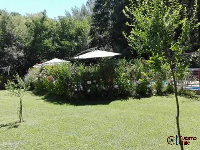 Jardín con sombrilla, flores y vista a la piscina en Cabañas Jardín Salto del Laja