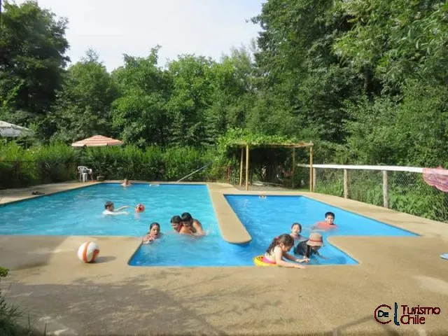 Niños nadando en la piscina con trampolín y sombrilla en Jardín Salto del Laja