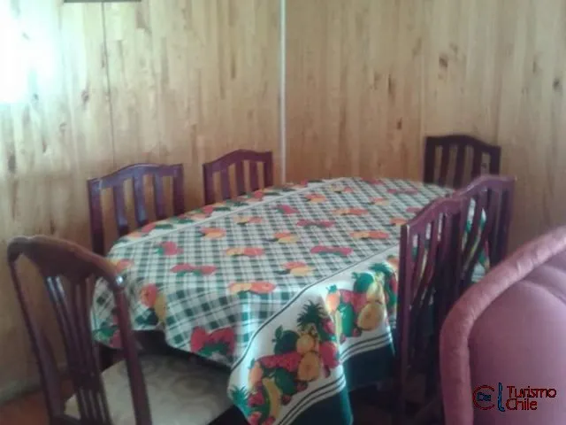 Comedor de cabaña con mesa redonda y sillas de madera en Jardín Salto del Laja