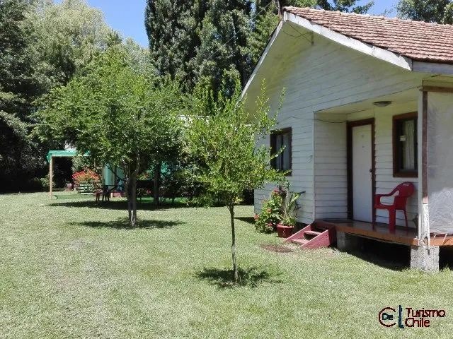 Cabaña blanca con jardín y glorieta al fondo en Cabañas Jardín Salto del Laja